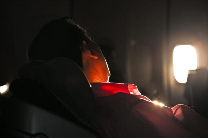 muž spí v sedadle letadla za svítání